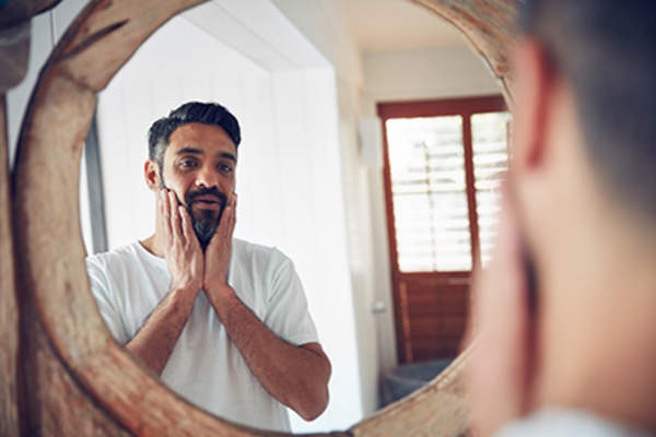 Man observing his skin in the mirror.