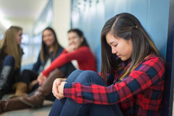 Girl getting bullied in high school hallway.
