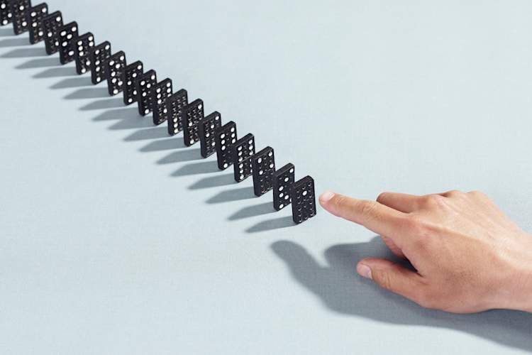 hand about to knock down line of dominoes