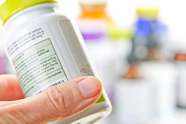 Woman holding supplement bottle.