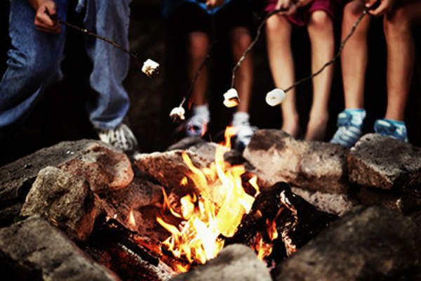 Children toasting marshmallows around a campfire.