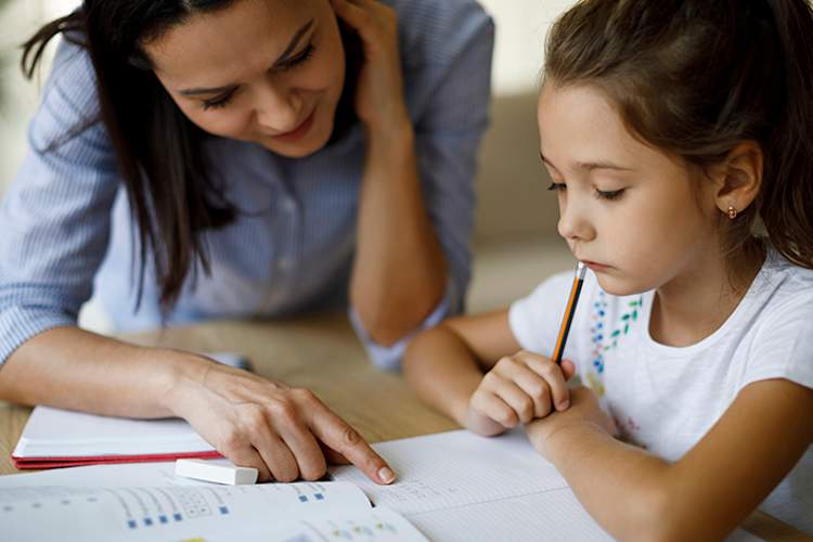 Mother helping her daughter with homework.