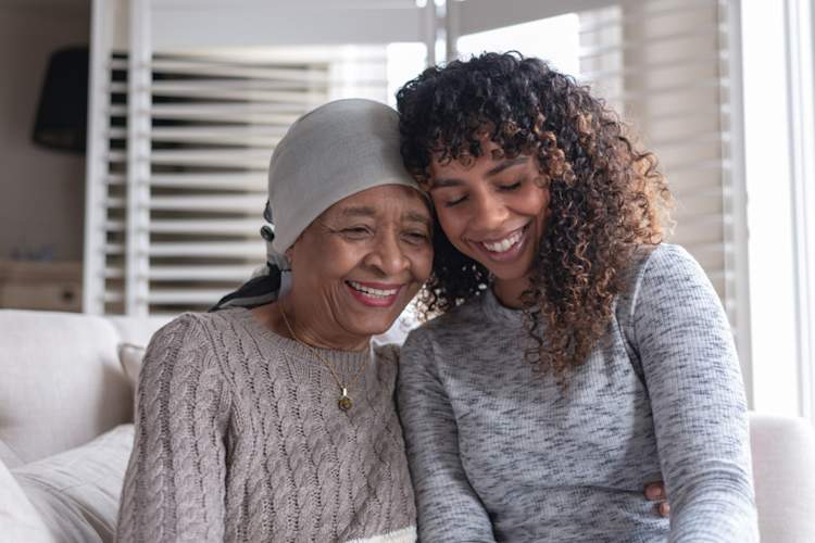 mother with cancer leaning on daughter, both smiling