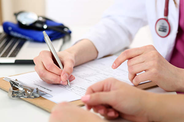 Doctor recording patient details on a clipboard.