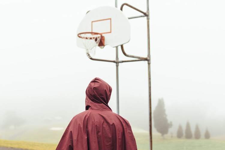 Person wearing raincoat standing in front of basketball hoop