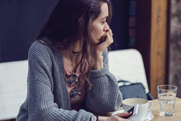Sad woman having coffee alone.