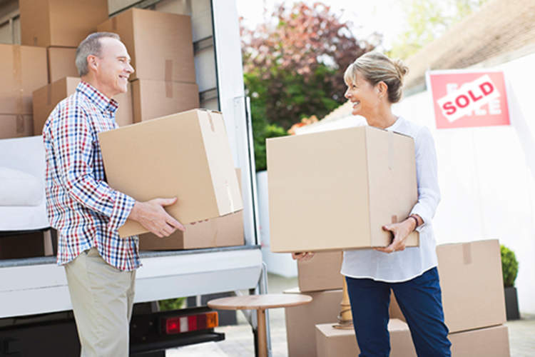 Couple unloading boxes from moving van