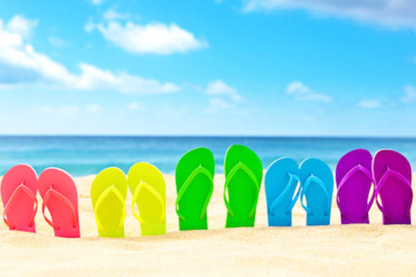 Brightly colored flip flops stuck in sand.