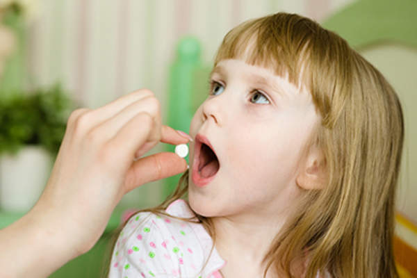 Child receiving a pill.