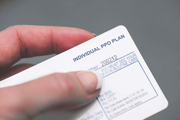 Woman holding health insurane card.