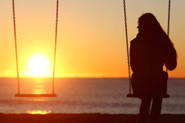 Single woman alone swinging on the beach