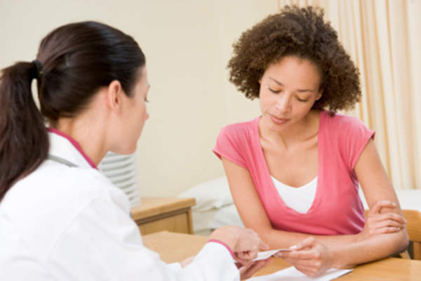 Doctor talking to young woman in office.