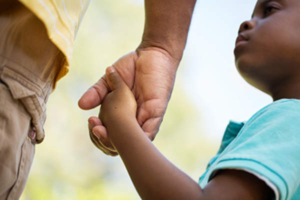 Father holding young child's hand.