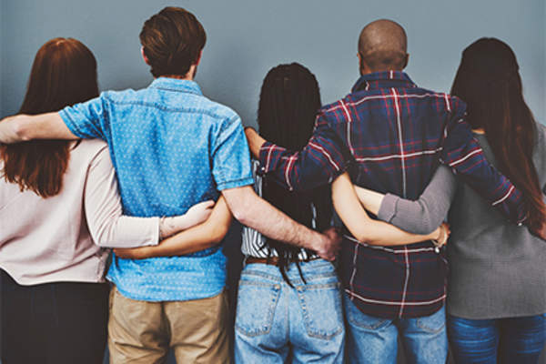 Diverse group of people with arms around each other in support.