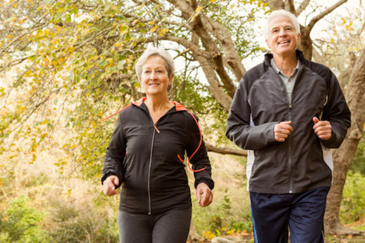 Happy retired couple jogging in park, depression isn't normal aging.