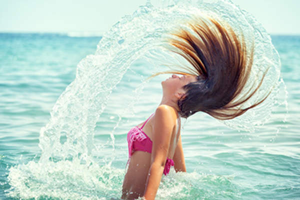 Girl flipping her hair out of the ocean.