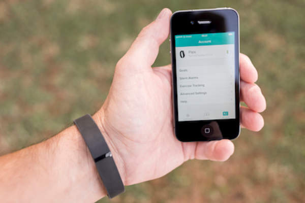 man using black Fitbit and smartphone