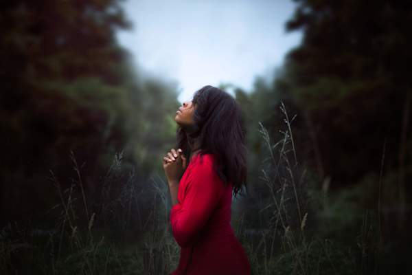 woman praying in the woods