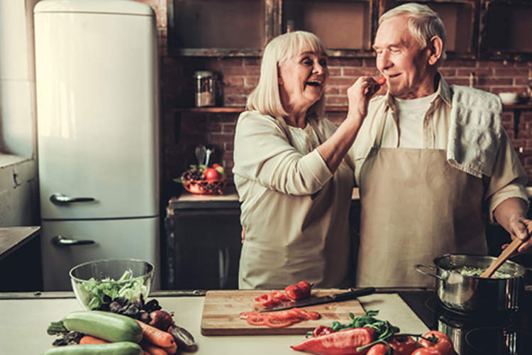 Happy senior couple cooking vegetables together.