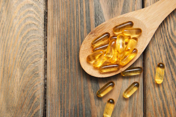 Fish oil vitamins on wooden spoon.