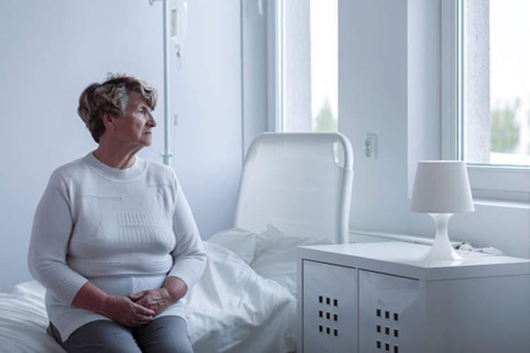 Unhappy woman patient in hospital looking out window.