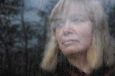Woman looking out rain covered window