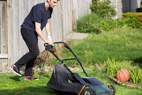 Teen boy mowing the lawn.