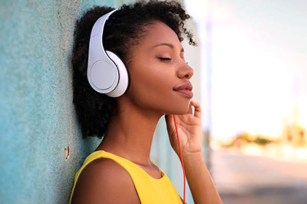 Young woman listening to music through headphones.