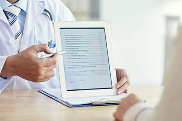 Doctor explains online patient survey on tablet.