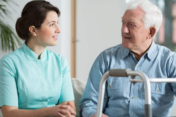 Elderly man talking to caregiver.