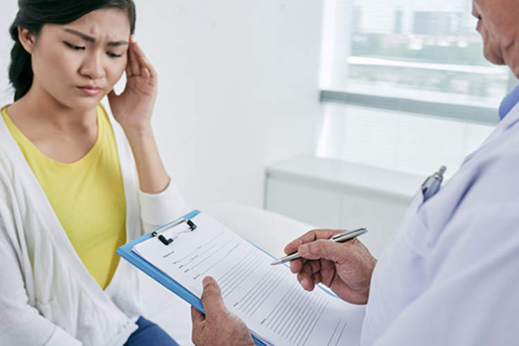 Young woman with migraine at doctors image.