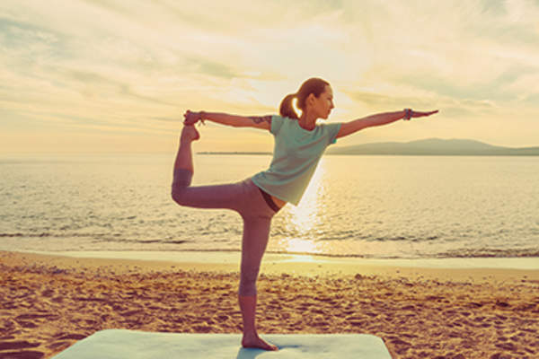 Young woman practicing yoga on the beach