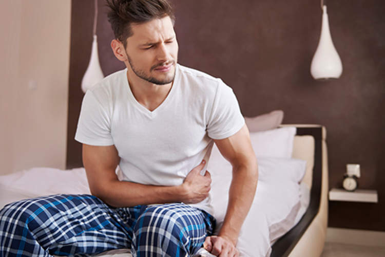Man experiencing abdominal pain in bed