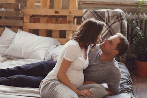 Pregnant couple being intimate.