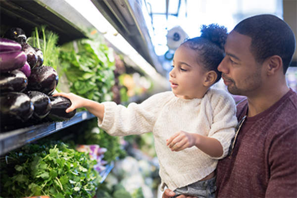 Dad and young daughter shopping for fresh produce.