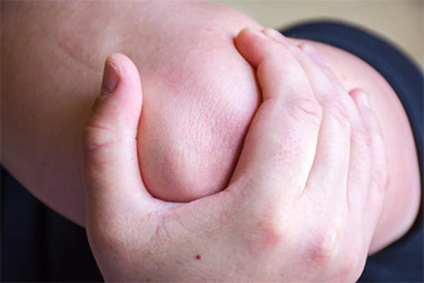 Hand holding knee in pain.