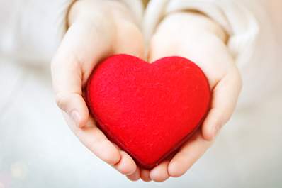 Child holding red heart in hands.