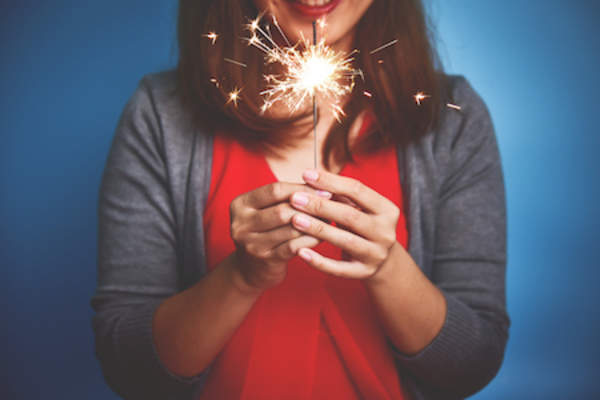 Woman holding lit sparkler.