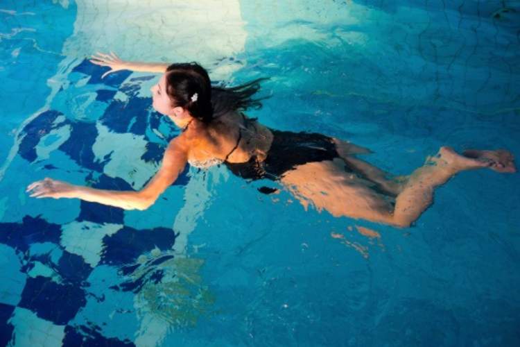 A woman swims in a pool to help her psoriatic arthritis.