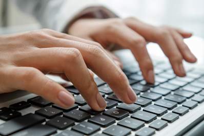 Hands typing on a laptop keyboard.