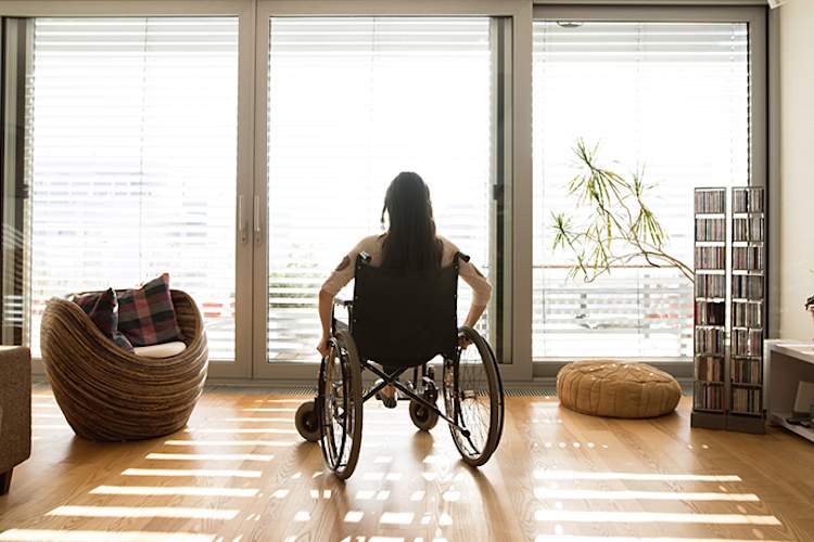 Woman in wheelchair in front of window.