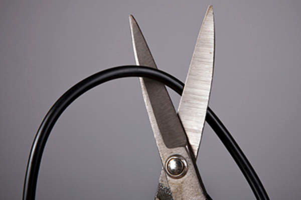 Close up of metal scissors cutting black wire.