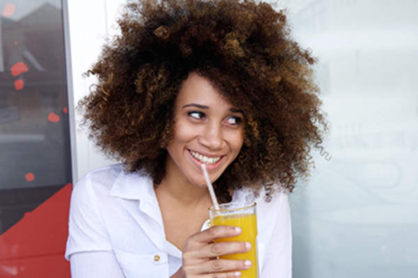 Smiling woman drinking juice through a straw.