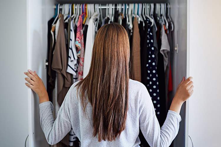 Young woman with long hair looking in her closet.