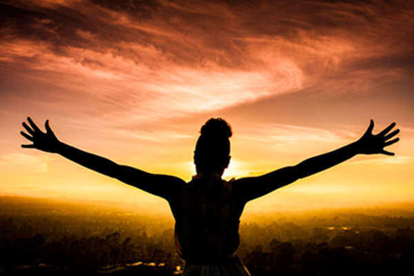 Woman arms out at sunset.