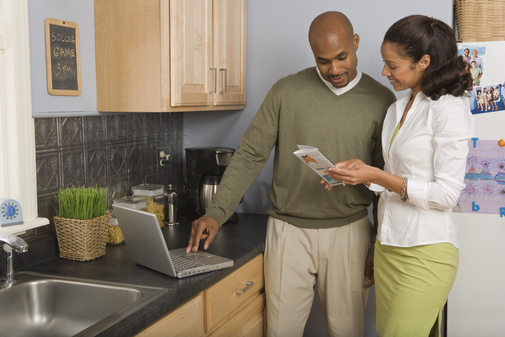 Couple in kitchen looking at travel brochure