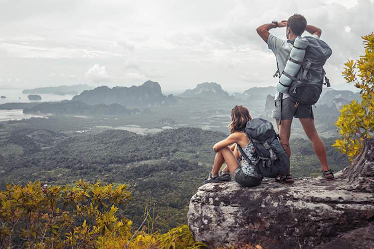 Man and woman on a rock looking out at a beautiful vista.