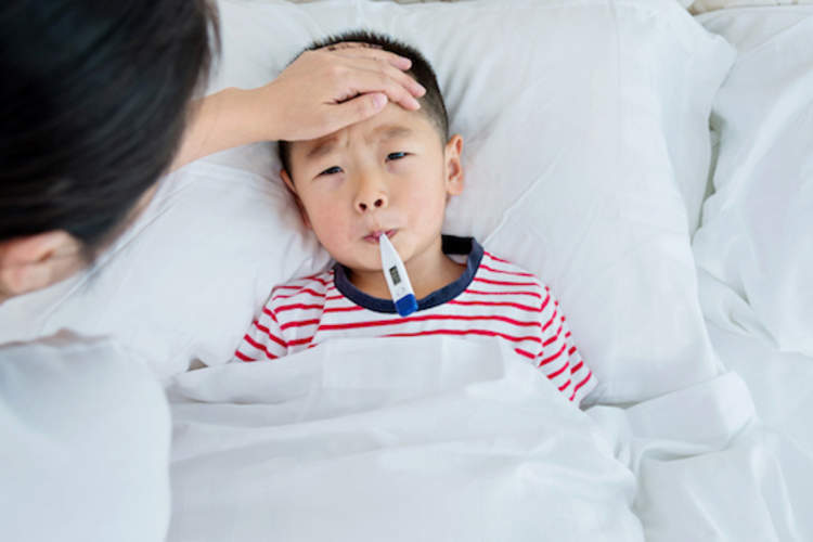 Sick child has his temperature taken by his mother.