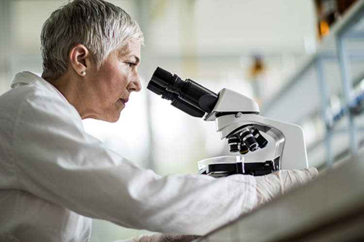 Below view of female scientist looking through a microscope