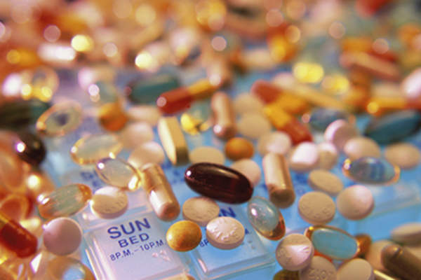 Assorted pills and supplements scattered around a pill box.